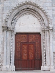 portale dell'abbazia dopo il restauro della facciata nel 2014; la lunetta fu scolpita da Ermenegildo Di Pirro, il portone è opera di don Peppe (foto Stefano Dark)